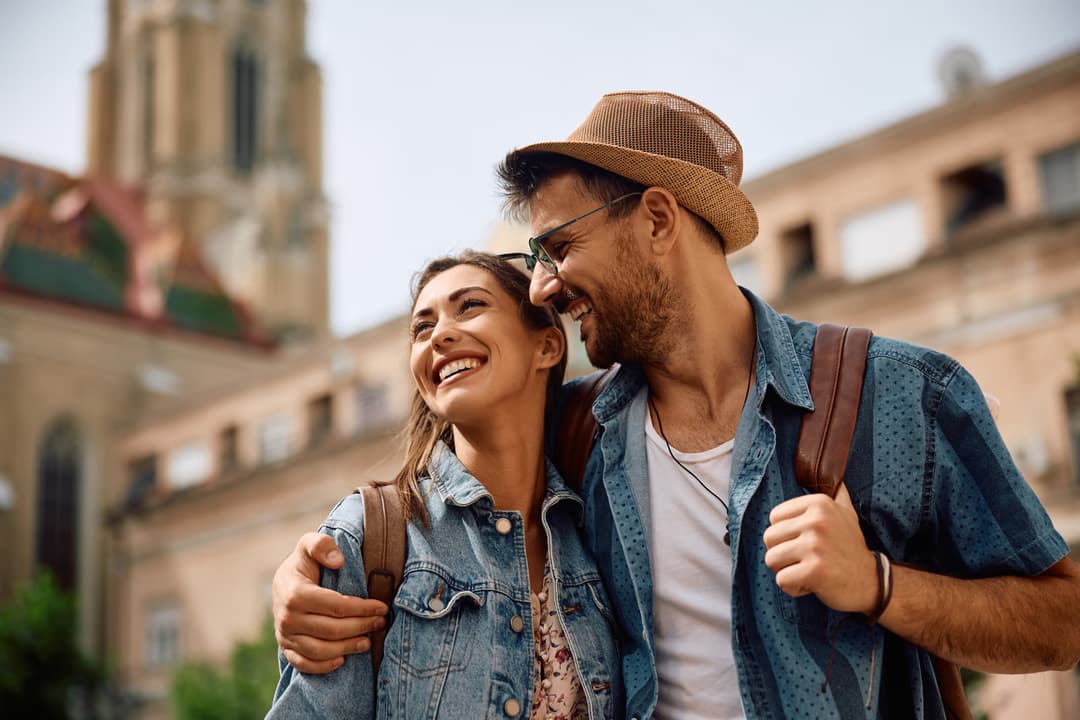 Happy couple of tourists walking embraced while sightseeing the town